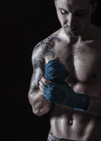 Close up of a boxer putting on straps preparing for combat on a dark backgroundの写真素材