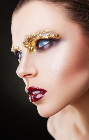 Young woman with makeup fashion. Eyes are adorned with liquid golden shadows or drops. Art makeupの写真素材