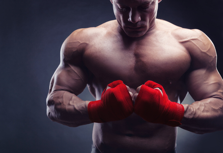 Boxing man ready to fight. Boxer with strong hands and clenched fists in red straps against a black backgroundの写真素材