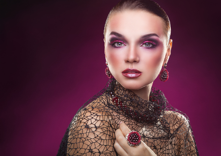 Beautiful young woman with fashion makeup and jewelry on a pink backgroundの写真素材