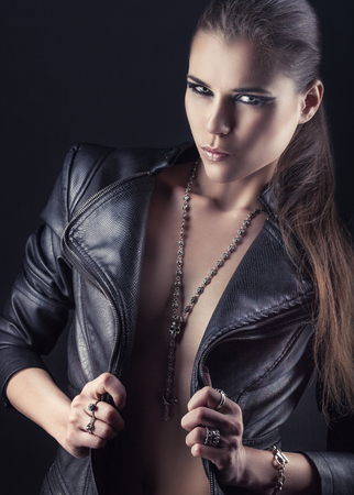 Girl rocker in a leather jacket and chain with a skull. Rocker woman makeup and accessoriesの写真素材