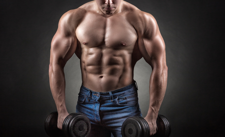 Bodybuilder. Fit muscular bodybuilder man exercising with dumbbell against a black backgroundの写真素材