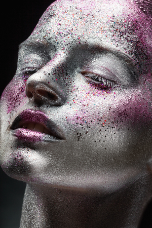 Fashion makeup. Close-up of a young woman with silver makeup with pink sequinsの写真素材