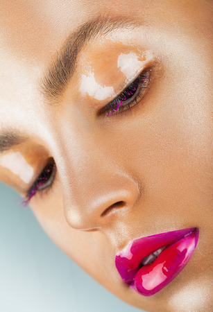 Close-up face of a beautiful woman with pink fashion make-up. Glossy transparent shadows and bright pink lipsの写真素材