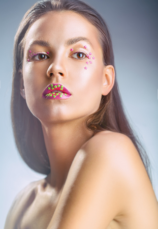 Portrait of a young woman with fashion make-up and decorative stars on her face on a gray backgroundの写真素材