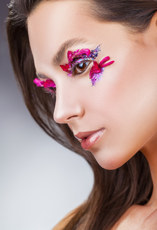 Beautiful young woman with fashion makeup against a gray backgroundの写真素材