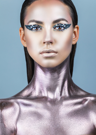 Portrait of a young woman with makeup fashion. Smokey eyes. Neck and chest are covered with metallic make-upの写真素材