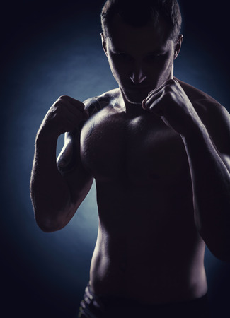 Silhouette of a boxer with clenched fists against a dark background. The concept of boxingの写真素材
