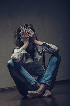 Young sad woman sitting alone on the floor in an empty roomの写真素材