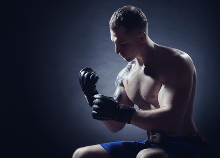 Boxer with boxing gloves sits before fight on a black background. Boxing conceptの写真素材