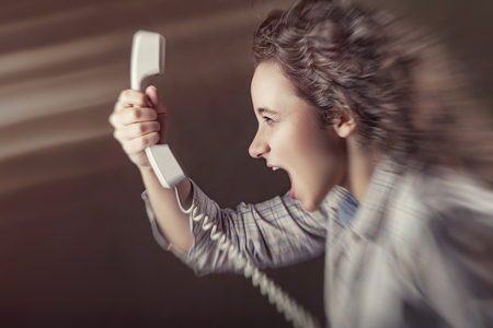 Young girl is screaming into the phone. Blurred backgroundの写真素材