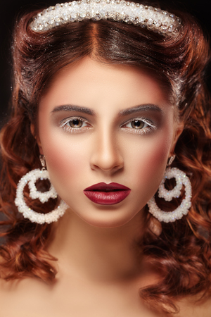 Beautiful young woman with wavy hair and fashion make-up and jewelryの写真素材