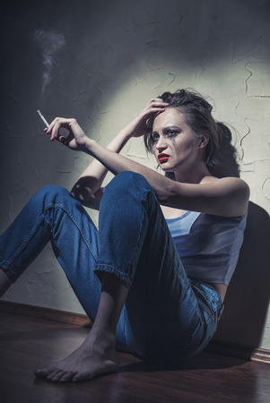 A young woman with a cigarette in his hand sitting on the floorの写真素材