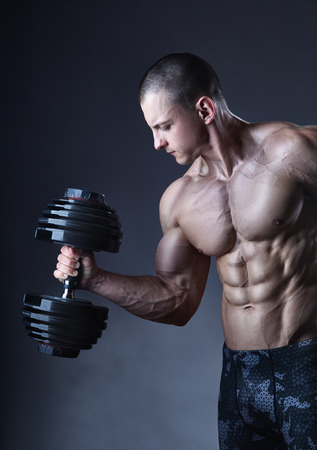 Bodybuilder. Fit muscular bodybuilder man exercising with dumbbellの写真素材