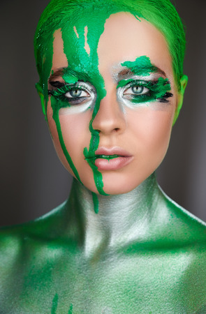 High fashion model. An amazing woman with green metallic makeup and leaking green neon paint. Glitter vivid makeupの写真素材
