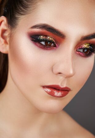 Fashion makeup. Closeup portrait of a girl of fashion model in trendy make-up. Eye models with colorful glitter on the eyelidsの写真素材
