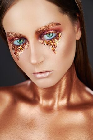 Gilded body. Golden makeup. Woman with golden makeup and bodyart. High fashion modelの写真素材