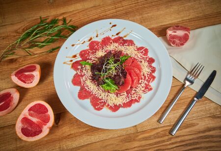 Beef carpaccio with grapefruit and lettuce. Arrangement with cutleryの写真素材