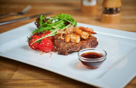 Grilling steak. Dish of meat on a plate adding with shrimp, tomatoes and saladの写真素材
