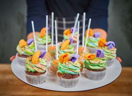 Delicious cupcakes dessert table served for birthday party. Cupcake decorated colored macaronsの写真素材