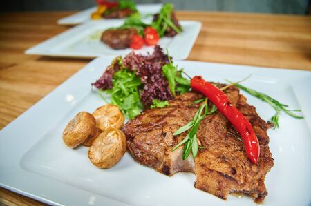Restaurant dishes. Grilling steaks. Dish of meat on a plate adding with mushrooms, salad and red pepperの写真素材