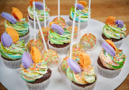Delicious cupcakes dessert table served for birthday party. Cupcake decorated colored macaronsの写真素材