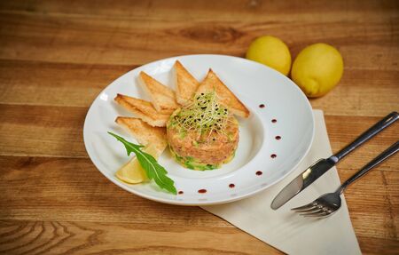 Delicious salmon tartare with avocado. Arrangement with a glass of wine and cutleryの写真素材