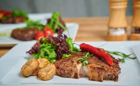 Grilling steak. Dish of meat on a plate adding with mushrooms, salad and red pepperの写真素材