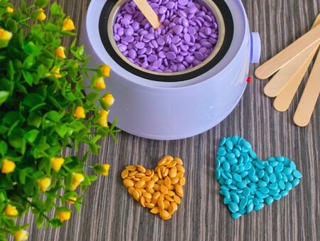 Wooden spatula in wax granules. Preparing for wax treatment. Beauty and fashion conceptの写真素材