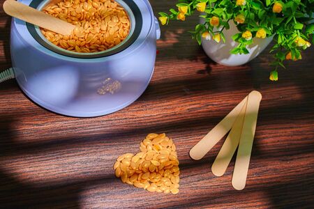 Wooden spatula in wax granules. Preparing for wax treatment. Beauty and fashion conceptの写真素材
