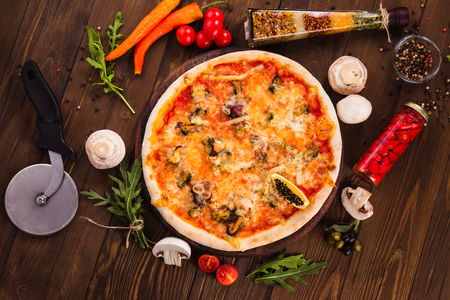 delicious Italian seafood pizza with ingredients on wooden table (top view)の写真素材