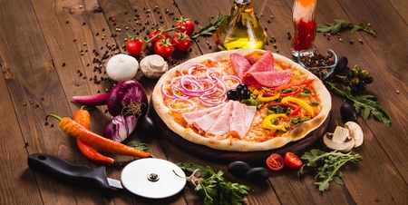 Italian Four Seasons Pizza (Quattro Stagioni) on the wooden background with ingredients around (close)の写真素材