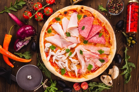 Meat Feast Pizza. Ham, Pepperoni, Beef and Chicken.  On a dark wooden background with ingredients around (close  top view)の写真素材