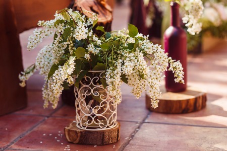 A bouquet of white lilac in a wrought-iron vase at a wedding ceremonyの写真素材