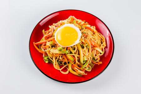 noodles with bacon, fried egg and pepper on a red plate on a white background. Traditional Italian pasta. Close top viewの写真素材