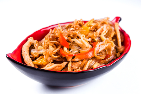 Thick glass noodles with chicken pepper and sesame seeds on a red plate on a white background. Traditional Italian pasta. Closeの写真素材