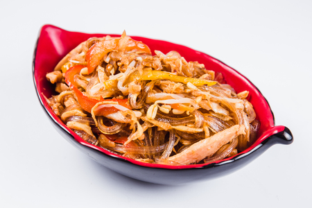 Thick glass noodles with chicken pepper and sesame seeds on a red plate on a white background. Traditional Italian pasta. Closeの写真素材