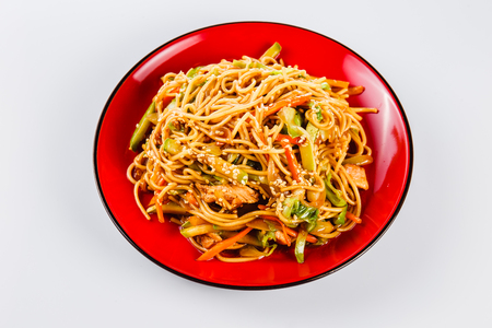 Noodles with pork, pepper and sesame seeds on a red plate on a white background. Traditional Italian pasta. Closeの写真素材