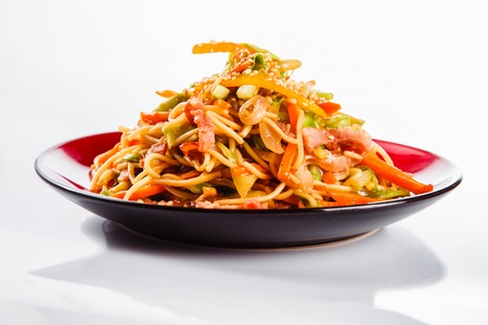 noodles with bacon, pepper and sesame seeds on a red plate on a white background. Traditional Italian pasta. Closeの写真素材