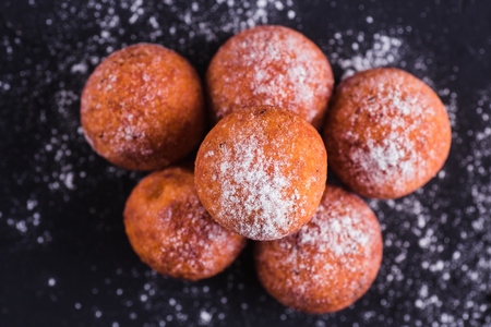 Curd balls sprinkled with sugar buds on a dark background (close top view)の写真素材