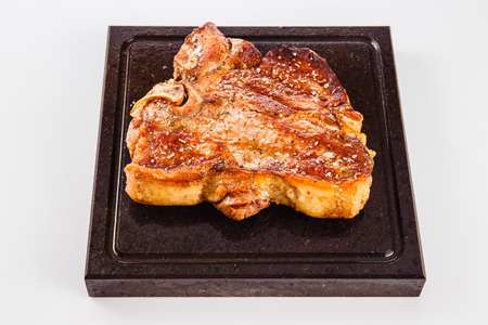 grilled meat steak on a hot granite plate on a white background (close)の写真素材