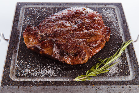 grilled meat steak on a hot granite plate on a white background (close)の写真素材