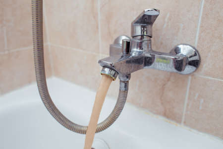 Dirty brown water flows from the tap in the apartmentの写真素材
