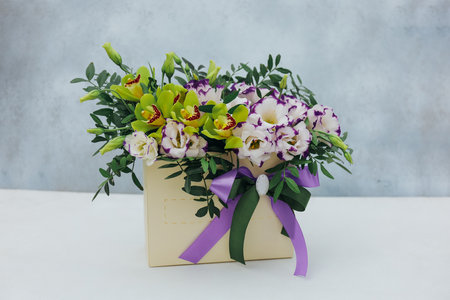 Bouquet of archidea and eustoma in a paper gift box on a gray background. In purple, white and yellow.の写真素材