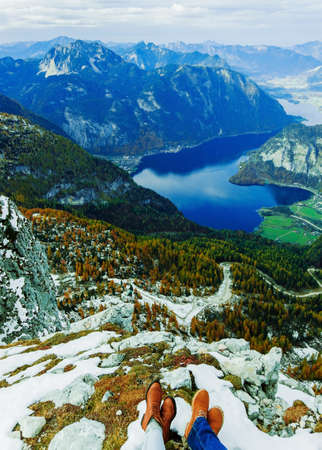 View from above to couple of shoes of the lovely pair. Love and travel concept. Hallstatter lake and among Alps mountains, Austria. Beautiful nature. Autumn season and trees with orange colour.の写真素材