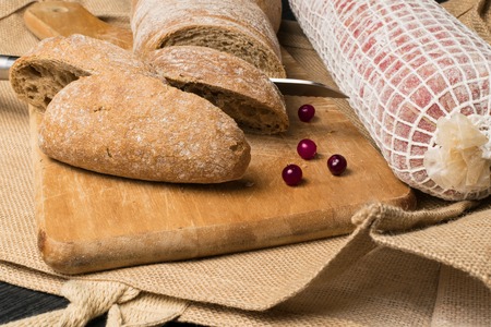 Ciabatta bread with salami in wooden boardの写真素材