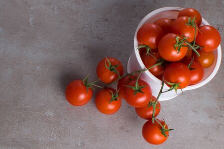 fresh red cherry tomatoes in white plastic box on grey board for backgroundの写真素材