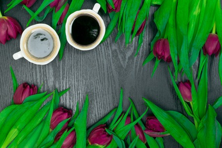 beautiful fresh spring tulip with cup of cofee on dark background. Coffee time. Flower giftの写真素材