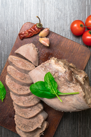 Boiled beef, pork tongue with cherry tomatoes, basil leaf, studio shot, isolated on wood background.の写真素材