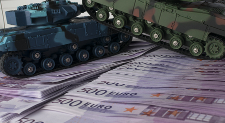 Close up green and blue tank toy placed on euro banknotes pile. business and economy war. new world war from business and economy concept. Concept of expense and cost of warの写真素材